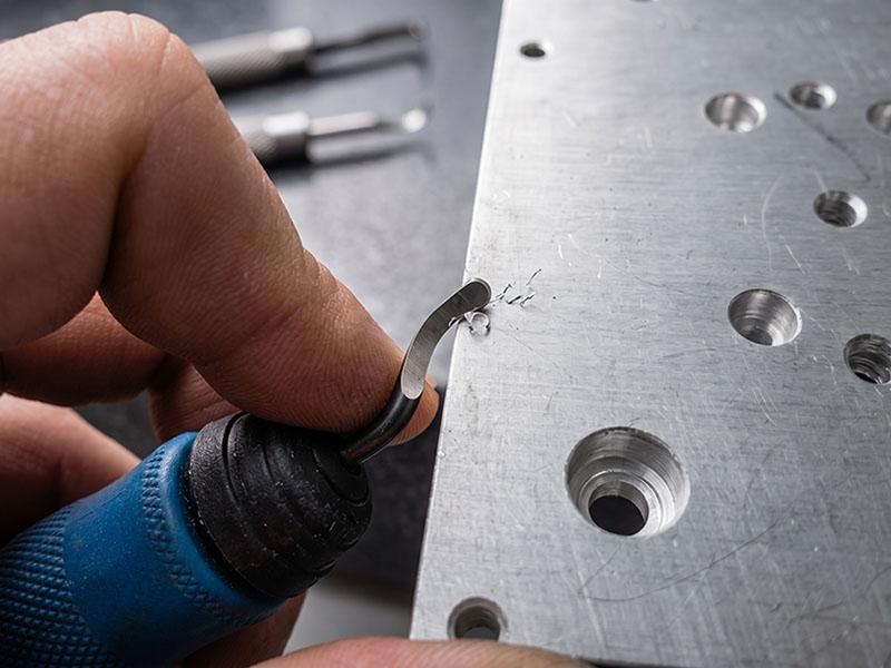 Manual deburring of metal parts to protect robotic wiring