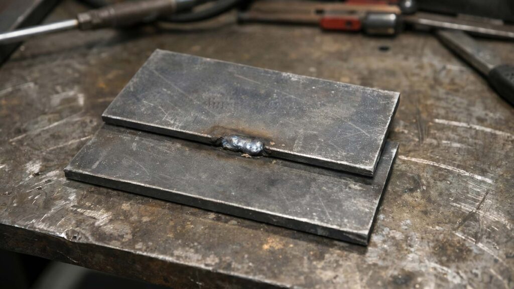 Close-up of a single tack weld joining two metal plates