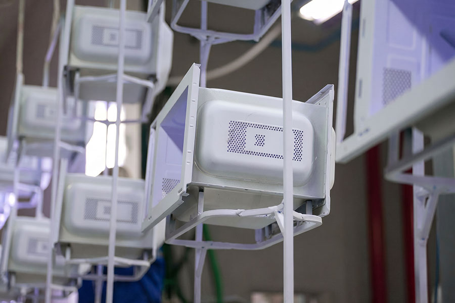 Coated metal components on a curing oven conveyor line