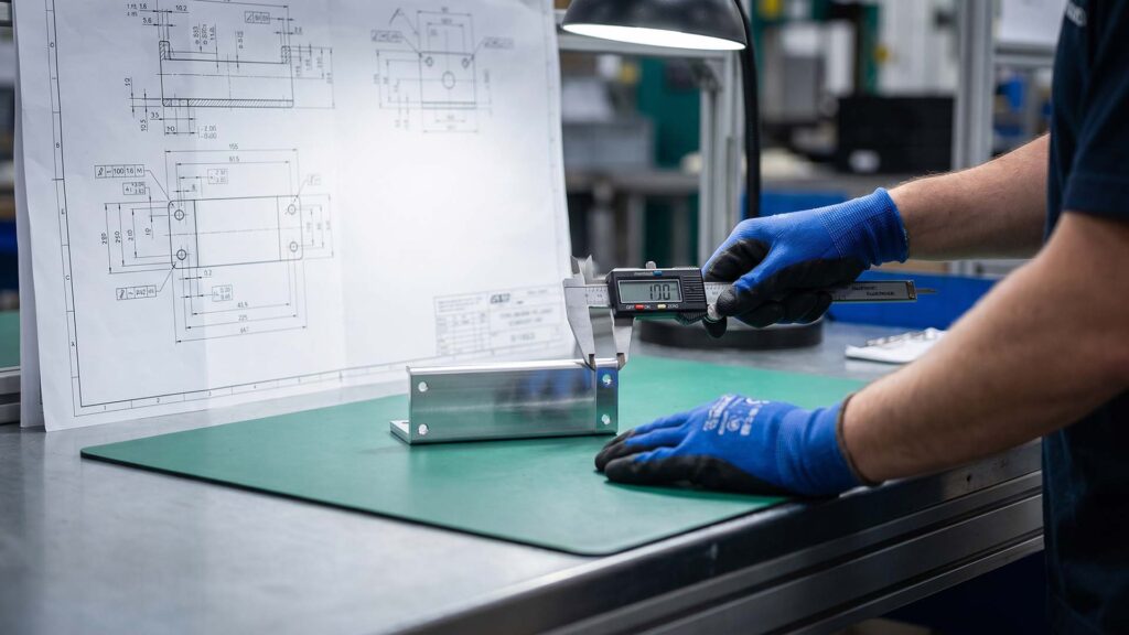 Ingeniør, der måler en metaldel med en digital skydelære