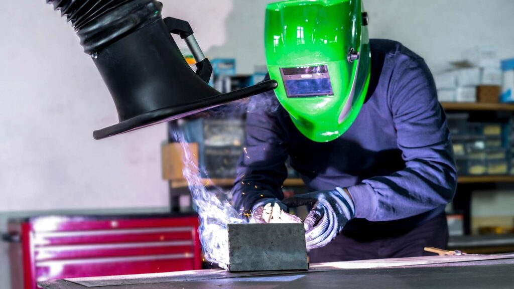 Welder using an industrial fume extractor to remove toxic smoke