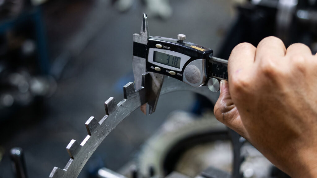 Inspector measuring sheet metal part with digital caliper