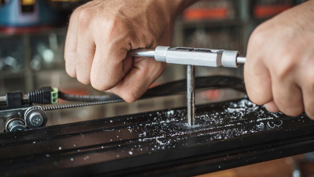 Manual thread tap tool re-cutting a metal hole