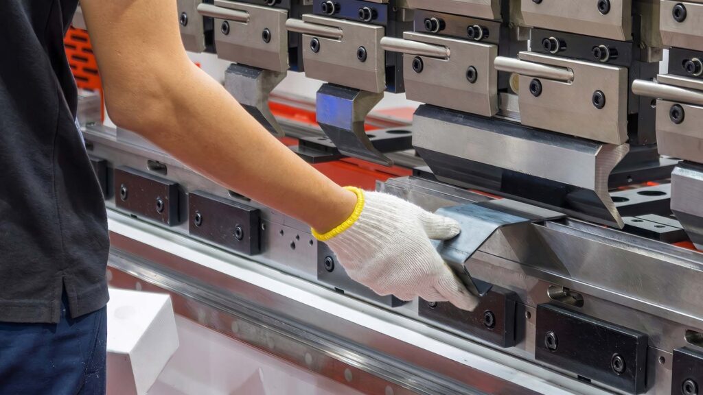 Worker operating CNC press brake in sheet factory