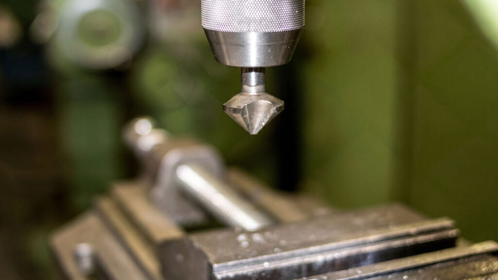 Countersink tool in machine chuck over metal