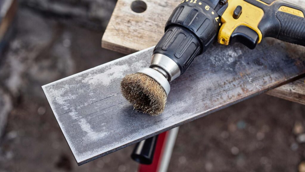 Electric wire brush cleaning a metal surface