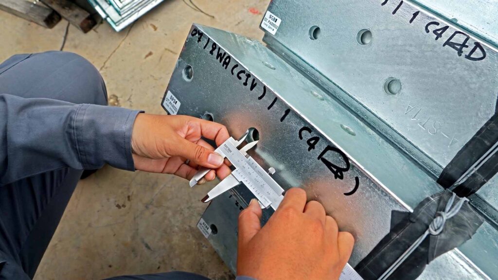 Engineer measuring hole on sheet metal with calipers