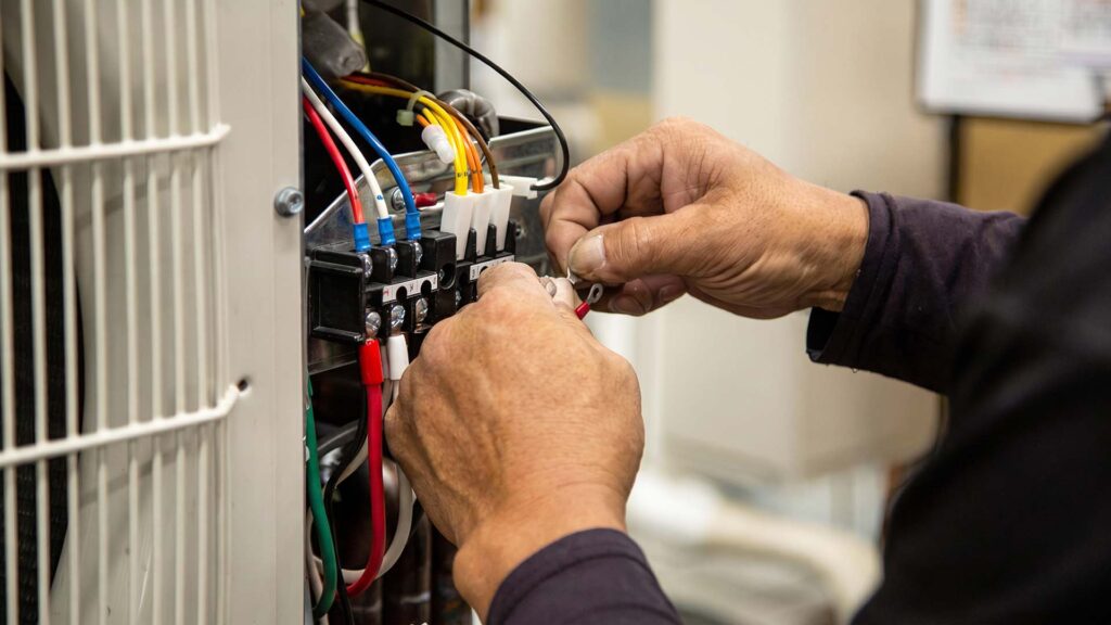 Hands connecting wires to a terminal block