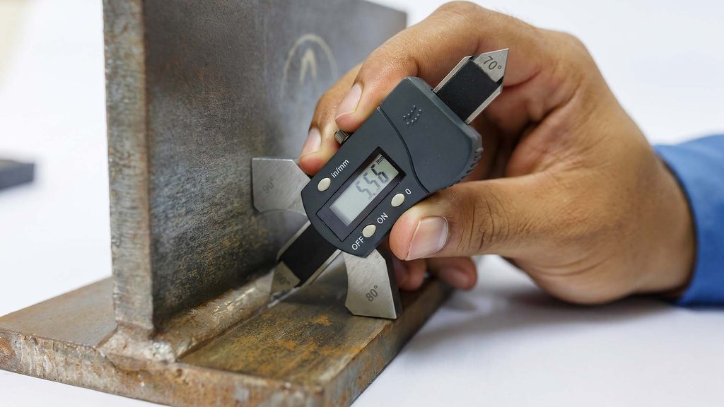 QC inspector measuring weld with digital gauge