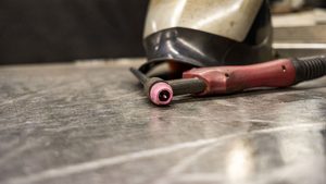 TIG welding torch and helmet on metal workbench