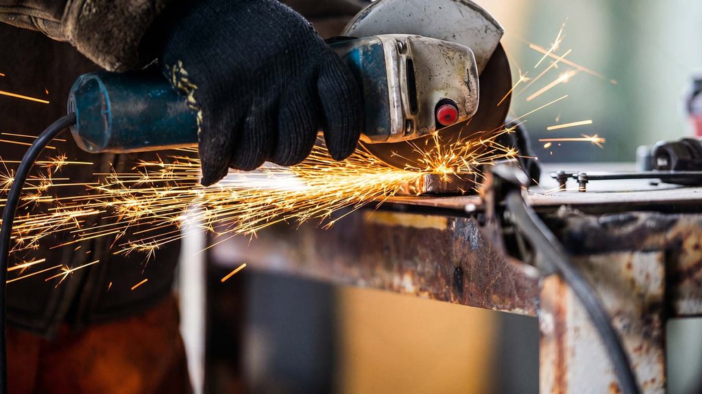 Worker grinding defective weld on sheet metal