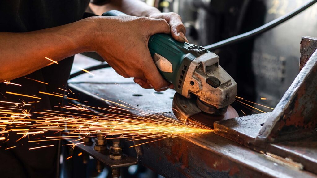 Worker rough grinding steel with an angle grinder